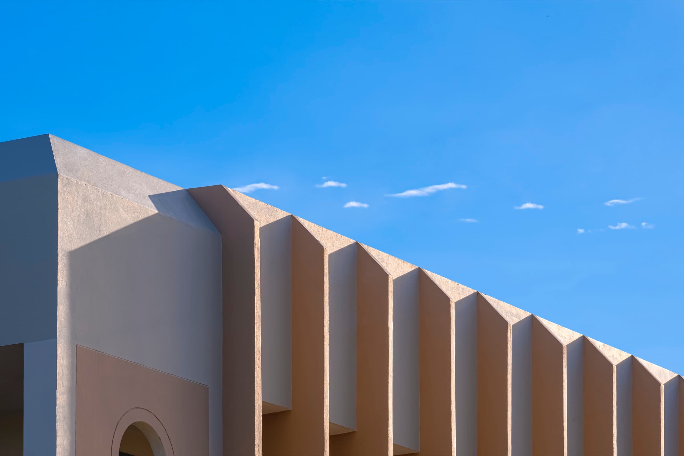 A row of identical warm concrete fins on a building edge, repeating in strict sequence