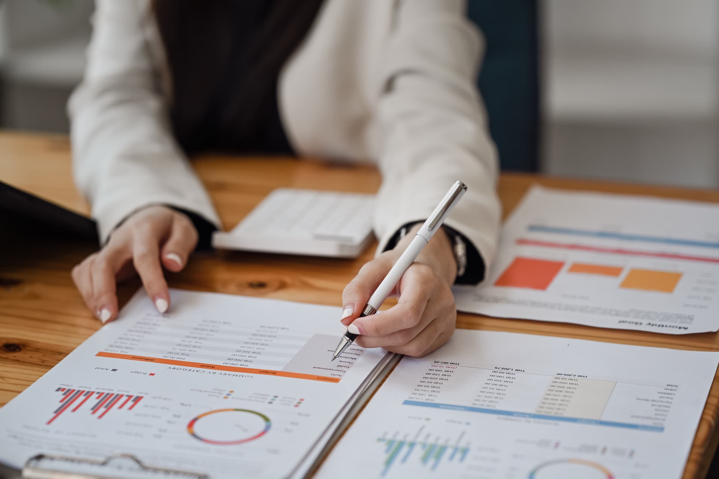 A person working through printed financial charts with a pen, annotating figures