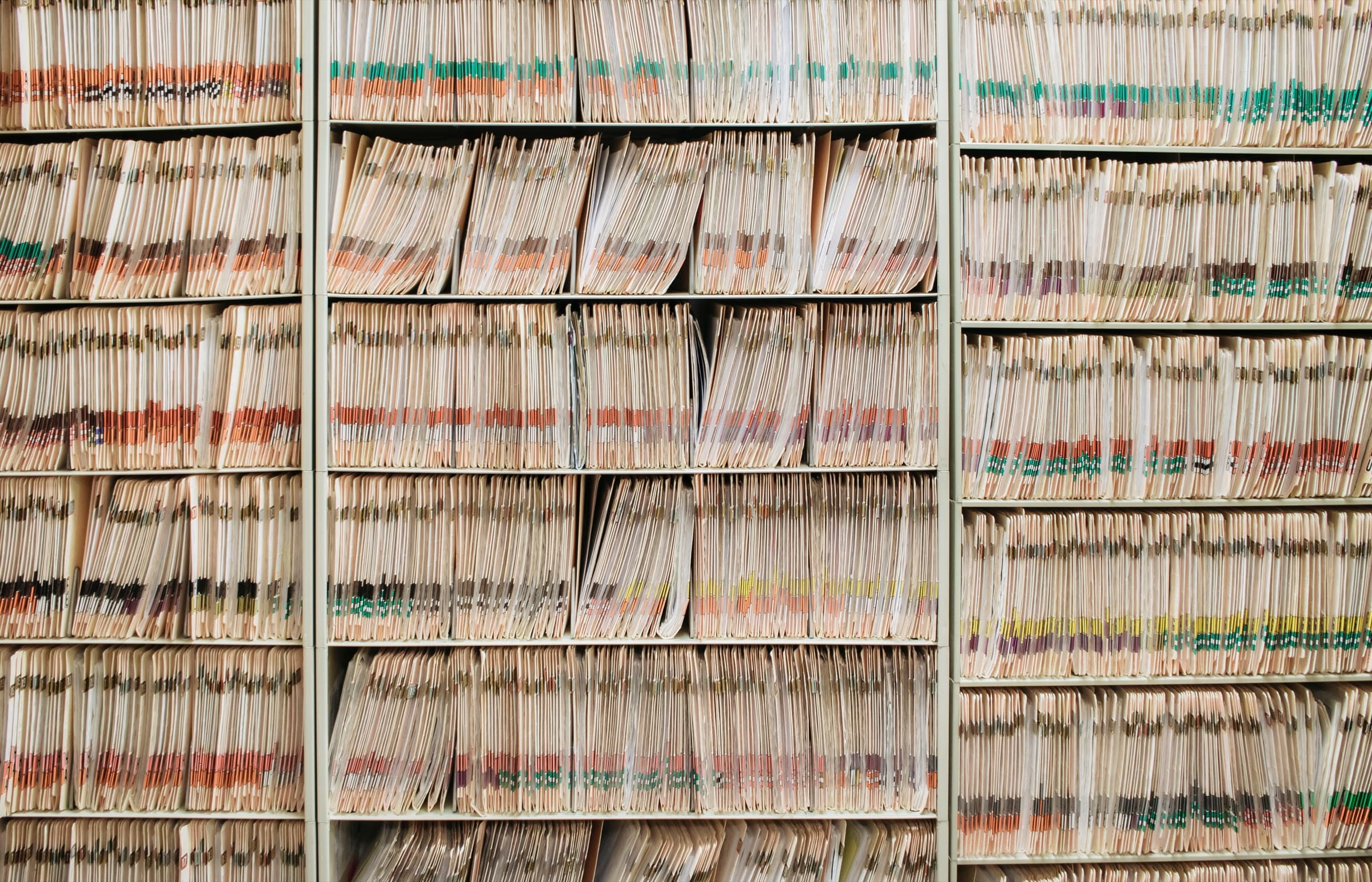 Floor-to-ceiling shelves densely packed with thousands of individual paper files